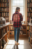 Person wearing a red plaid shirt with 'Teacher Strong' in a library