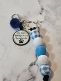 Keychain with paw print charm and checkered beads on a marble surface