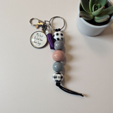 Keychain with beads and decorative elements on a light surface with a plant in the background