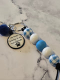Keychain with blue and white checkered beads and a paw print charm on a marble surface