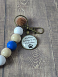 Keychain with paw print design and text on a wooden surface