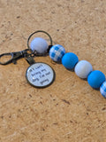 Keychain with blue, white, and checkered beads on a cork background