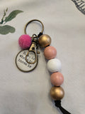 Keychain with beads and a pom-pom on a beige background