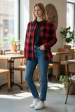 Woman wearing a red and black plaid shirt, blue jeans, and white sneakers in a cafe.