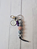 Keychain with beads and a tag on a light wooden surface