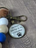 Keychain with paw print design and text on a wooden surface