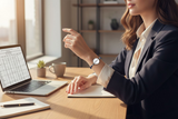 Woman in a professional setting using a laptop with a watch on her wrist.