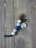 Keychain with colorful beads and a circular tag on a wooden surface
