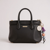 Black handbag with decorative keychain on a light gray background