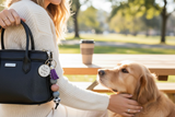 Person holding a black handbag with a dog at a park table