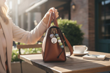 Brown handbag with decorative elements on a wooden table outdoors