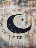 Plaid fabric with a black moon and star design and text on a beige background