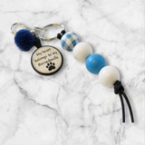 Keychain with paw print design and decorative beads on a marble background