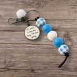 Keychain with blue and white checkered beads and a circular tag on a wooden surface