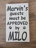Decorative sign with text 'Marvin's guests must be approved by Milo' on a wooden surface