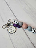 Keychain with beads and a tag on a light wooden surface