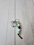 Beaded keychain with paw print charm on a light wooden surface