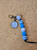 Keychain with blue and white checkered beads on a cork background