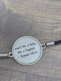 Necklace with pendant featuring a quote by Stevie Nicks on a wooden surface